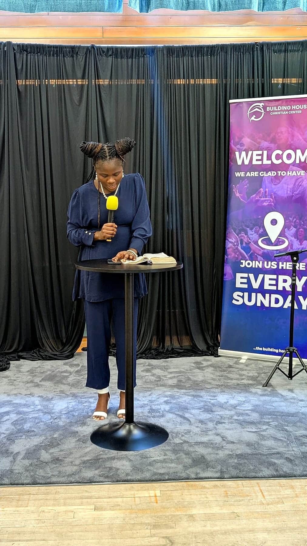 Addressing the congregation at BHCC, the welcome banner behind
